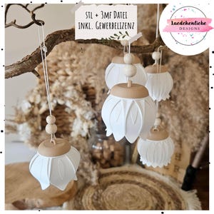Op de afbeelding: Een set witte, klokvormige hangende ornamenten met beige, platte doppen en twee kleine houten kralen aan het koord. De tekst "STL + 3MF DATEI INKL. GEWERBELIZENZ" is zichtbaar op een briefje, en een logo toont "laedchenliebe DESIGNS".