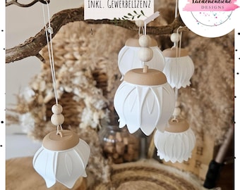 Puede incluir: Un conjunto de adornos colgantes blancos en forma de campana con tapas planas de color tostado y dos pequeñas cuentas de madera en el cordel. El texto "STL + 3MF DATEI INKL. GEWERBELIZENZ" y el logo "laedchenliebe DESIGNS" son visibles.