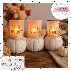 Può includere: Tre portacandele in vetro smerigliato, ciascuno poggiato su una base a forma di zucca in ceramica bianca. I cilindri presentano scritte nere che recitano "cozy Autumn", "pumpkin season" e "fall in love", decorate con nastri e fiori secchi.