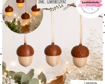 May include: Three hanging acorn ornaments with brown caps and light beige bases, suspended by thin ribbons. One acorn features a smooth cap, one has a heart detail, and one has a textured cap. Text includes STL + 3MF DATEI INKL. GEWERBELIZENZ and 2 VARIANTEN: HOHL FÜR BALLONLICHTER & GESCHLOSSEN.