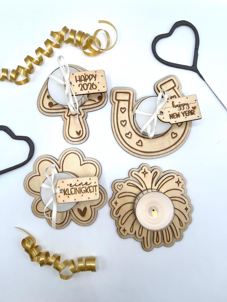 May include: A collection of wooden candle holders and decorations for the New Year. The set includes a number 4, a horseshoe, a flower, and a firework design, each with a tea light candle. The decorations have the phrases "Happy 2026" and "Happy New Year".
