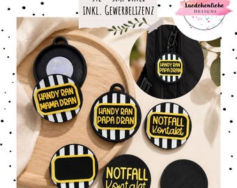 Puede incluir: Una colección de etiquetas circulares a rayas blancas y negras con detalles en amarillo. Las etiquetas incluyen el texto "HANDY RAN MAMA DRAN", "HANDY RAN PAPA DRAN" y "NOTFALL KONTAKT". Algunas tienen marcos amarillos vacíos.