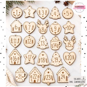 Puede incluir: Un conjunto de veinticuatro adornos de madera de color claro para calendario de adviento con formas variadas como estrellas, corazones, árboles, casas, campanas, tazas y cabezas de reno, cada uno grabado con un número del uno al veinticuatro.