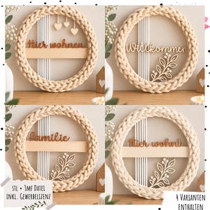 Puede incluir: Un adorno de pared circular con un marco de hilo beige grueso trenzado y cuerdas blancas verticales. El centro muestra recortes de madera con el texto en alemán Hier wohnen, Willkommen, Familie o Hier wohnt, junto a motivos decorativos de corazones u hojas.