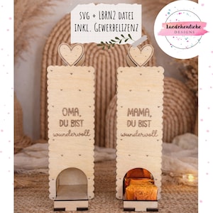 Puede incluir: Dos cajas de regalo de madera con adornos en forma de corazón. Una caja dice "OMA, DU BIST wundervoll" y la otra dice "MAMA, DU BIST wundervoll". Las cajas tienen un borde festoneado y una pequeña abertura en la parte inferior.