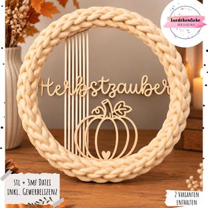 Può includere: Una ghirlanda decorativa circolare con un bordo spesso in filato intrecciato color crema. All'interno, un intaglio in legno chiaro mostra il testo tedesco "Herbstzauber" sopra un'illustrazione a linee di una zucca con listelli verticali.