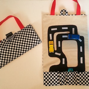 以下が含まれることがあります： 黒と白の市松模様の布製プレイマットで、レースコースのデザインが施されています。マットは赤いハンドル付きのトートバッグに折り畳むことができます。マットには、おもちゃの車を収納するためのポケットが付いています。