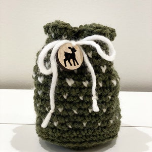 May include: A green crocheted drawstring bag with white polka dots and a wooden button featuring a deer silhouette.