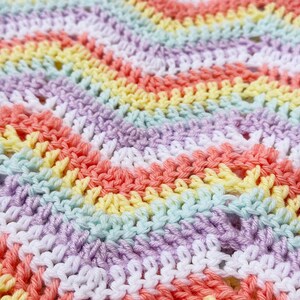 Può includere: Primo piano di un tessuto all'uncinetto con un motivo a righe arcobaleno in tonalità di bianco, giallo, verde chiaro, lavanda e corallo.
