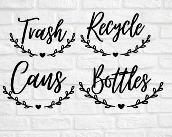 May include: Four black and white signs with a leafy wreath design and a heart. The signs read "Trash Cans", "Recycle Bottles", "Trash", and "Recycle".