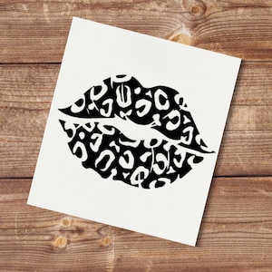 May include: A black and white print of lips with a leopard print pattern. The lips are on a white background, and the image is set against a wooden surface.
