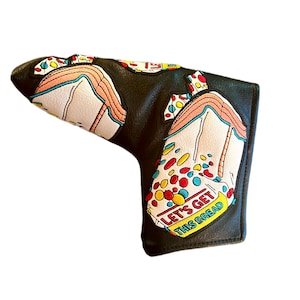Puede incluir: Cubierta de cabeza de palo de golf de cuero negro con un diseño colorido de una caja de cereales con el texto "Let's Get This Bread".