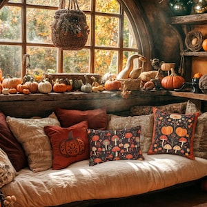 Könnte beinhalten: Ein gemütliches, herbstliches Interieur mit einem Fenster mit Blick auf das Herbstlaub. Ein Sofa ist mit Kissen geschmückt, darunter einige mit Kürbis- und Pilzmotiven. Kürbisse und Kürbisse sind im ganzen Raum angeordnet und schaffen eine warme, einladende Atmosphäre.