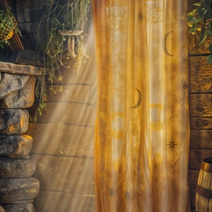 Pode incluir: Uma sala de madeira r&uacute;stica com uma cortina amarela transparente com desenhos de lua e estrelas. A luz do sol atravessa a cortina, iluminando a sala com uma luz dourada.