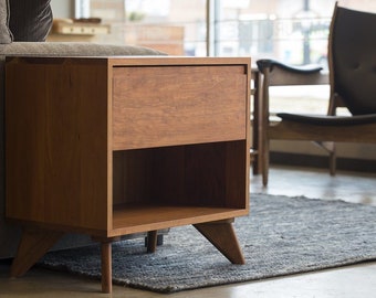 May include: A wooden end table with a single drawer and a lower shelf. The table has a light brown finish and four tapered legs.