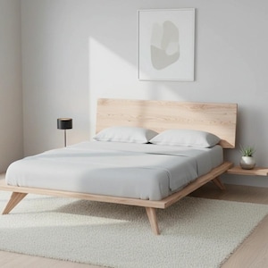 May include: A contemporary wooden bed with a light grey duvet and two white pillows. The bed is on a white rug. A small side table with a plant is attached to the bed frame.