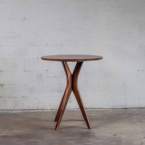 May include: A round wooden table with a dark brown finish and a unique X-shaped base.