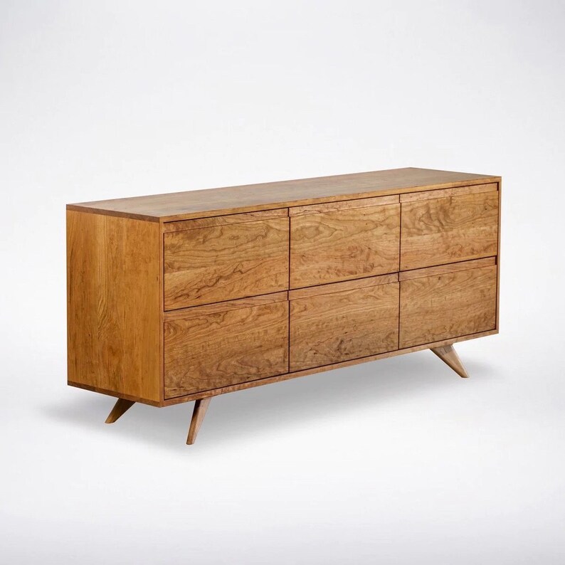 May include: A wooden dresser with six drawers and tapered legs. The dresser is made of light brown wood with a natural finish.
