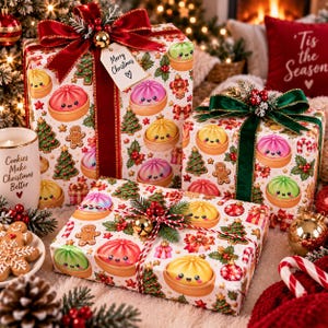 May include: Three rectangular gift boxes wrapped in white paper featuring a pattern of colorful cartoon dumplings, gingerbread men, and Christmas trees. The boxes are adorned with red and green ribbons, bows, and a tag reading Merry Christmas.