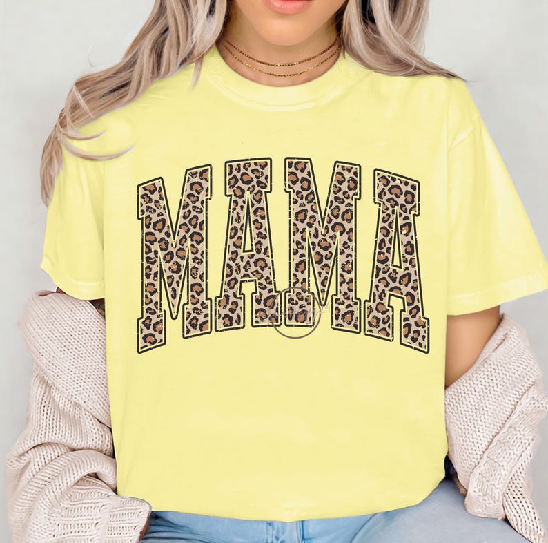 K&ouml;nnte beinhalten: Gelbes T-Shirt mit kurzen &Auml;rmeln und dem Wort "MAMA" in gro&szlig;en schwarzen Buchstaben mit Leopardenmuster.