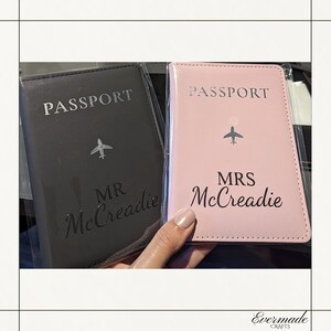 Peut inclure: Deux porte-passeports, un noir et un rose, avec le mot "PASSPORT" imprimé sur le devant. Le porte-passeport noir a "MR McCreadie" imprimé dessus, et le porte-passeport rose a "MRS McCreadie" imprimé dessus.