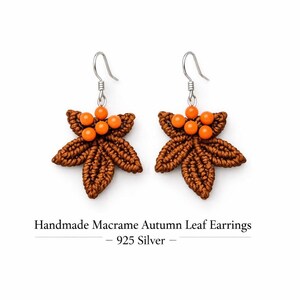 Può includere: Un paio di orecchini in macramè fatti a mano a forma di foglie autunnali. Gli orecchini sono marroni con accenti di perline arancioni e ganci argentati. Il testo "Handmade Macrame Autumn Leaf Earrings - 925 Silver" è sotto.