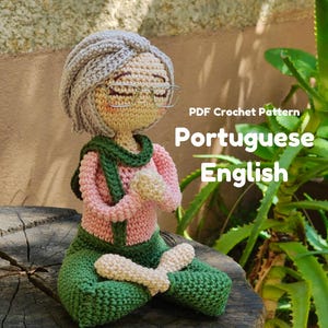 Könnte beinhalten: Gehäkelte Puppe in einer sitzenden Yoga-Pose, mit einem rosa Oberteil, grüner Hose und einem grünen Schal. Die Puppe hat graues Haar, eine Brille und sitzt auf einer Holzoberfläche. Der Text auf dem Bild lautet "PDF Crochet Pattern Portuguese English."