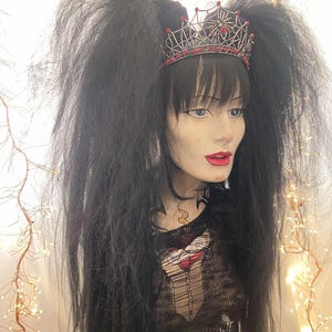 May include: A black wig with two long, thick pigtails. The wig is styled with a black and red spiderweb crown with red jewels.