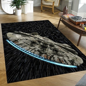 Puede incluir: Una alfombra en blanco y negro con una imagen detallada de la nave espacial Millennium Falcon volando por el espacio. La nave espacial está rodeada de un campo de estrellas y rayas de luz.
