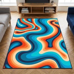 Puede incluir: Una alfombra rectangular con un diseño retro. Presenta un patrón ondulado de olas azules, naranjas y crema, bordeado por un borde negro. La alfombra está colocada sobre un suelo de madera, añadiendo un toque de color a la habitación. Las dimensiones de la alfombra son en centímetros.