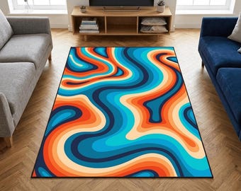 May include: A rectangular area rug with a vibrant, retro-inspired design. The rug features a swirling pattern of blue, orange, and cream-colored waves, bordered by a black edge. The rug is placed on a hardwood floor, adding a pop of color to the room.