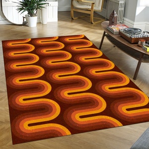 Puede incluir: Una alfombra marrón y naranja con un patrón ondulado abstracto. La alfombra tiene un estilo retro de los años 70.
