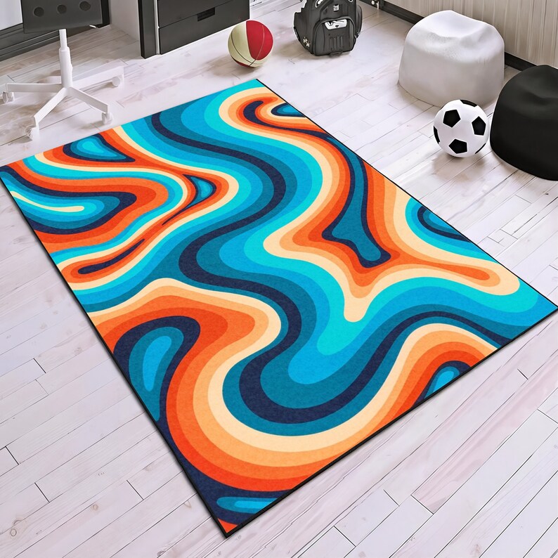 May include: A rectangular area rug with a retro, wavy design in shades of blue, orange, and cream. The rug features a dark blue border and a pattern reminiscent of flowing water or layered terrain. The rug is placed on a light wood floor.