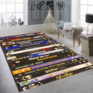 May include: A black and white rug featuring a design of stacked VHS tapes with titles of popular horror and fantasy films, including "Halloween", "Beetlejuice", "Scream", "Ghostbusters", and "The Nightmare Before Christmas".