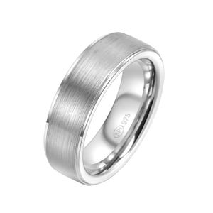 May include: A silver band ring with a brushed finish and a beveled edge. The inside of the band is stamped with "SP1 925".