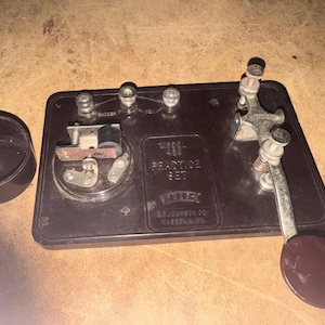 May include: A vintage Model 450 practice set by Bailey, with a dark brown base and a separate cup. The set includes a key, knobs, and a lever. The text "Bailey" and "E.H. Johnson Co. Warren, PA" are visible.