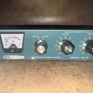 May include: A Heathkit HD-18 Brid Phone Patch with a VU meter, three knobs labeled "RCVR", "GAIN", and "TRANS", and a switch labeled "OFF" and "ON".
