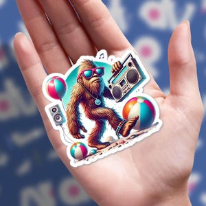 May include: A colorful sticker featuring a cartoon Bigfoot wearing sunglasses and holding a boombox. The Bigfoot is walking on a beach with beach balls and a speaker. The sticker has a white border.