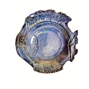 May include: A ceramic fish-shaped serving dish with a blue and gold glaze. The dish features a detailed design of a fish, including fins, scales, and an eye. The dish is approximately 10 inches in diameter.