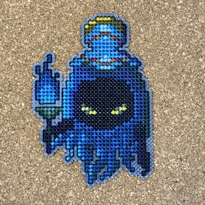 May include: Blue and black cross-stitch pattern of a ghost with a face peeking out from under the hood.