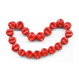 May include: A strand of bright red, glossy, ceramic beads in the shape of a heart. The beads are smooth and have a slightly irregular shape.