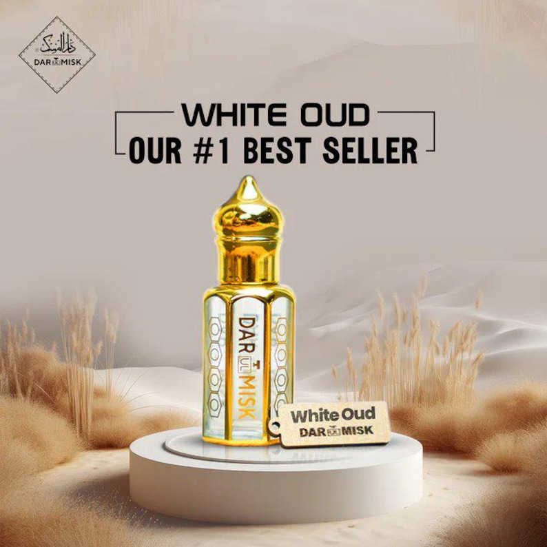 May include: A gold-topped perfume bottle labeled "White Oud" and "DAR MISK" sits on a white pedestal. The bottle is clear with gold accents and a decorative design. The background features text that reads "OUR #1 BEST SELLER".