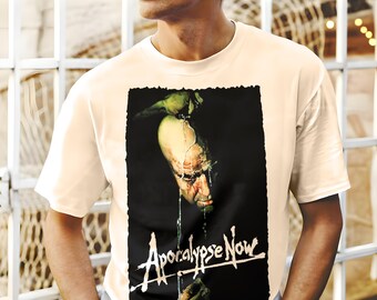 Könnte beinhalten: Ein weißes T-Shirt mit einem schwarzen und grünen Grafikdruck eines Männergesichts mit dem Text "Apocalypse Now" in Weiß.