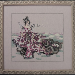 Könnte beinhalten: Kreuzstich-Kunstwerk einer Frau in einem floralen Kleid mit langer Schleppe. Das Kleid hat ein Muster aus burgunderfarbenen Blumen auf cremefarbenem Hintergrund. Das Kunstwerk ist in einem goldfarbenen, verzierten Rahmen vor einem blassrosa Hintergrund gerahmt.