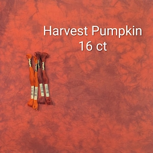 Puede incluir: Una pieza de tela jaspeada en color naranja y rojo oscuro con una textura tejida visible, acompañada de cuatro madejas de hilo de bordar en tonos naranja y rojo a juego. El texto Harvest Pumpkin 16 ct está impreso en blanco sobre la tela.