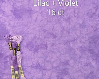 Pode incluir: Uma peça de tecido para ponto cruz de 16 ct com um padrão tie-dye mesclado em lilás e violeta. Três meadas de linha de bordar em tons de roxo coordenados estão colocadas à esquerda. O texto "Lilac + Violet 16 ct" é visível.