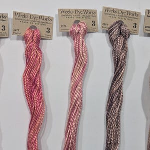 以下が含まれることがあります： さまざまな色のWeeks Dye Works Pearl Collectionの糸が5かせ。各かせには番号と色名がラベル表示されています。色は濃い赤から明るい茶色まであり、「Liber」、「Peony」、「Sweetheart」、「Mauve」、「Thistle」と表示されています。