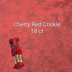 Puede incluir: Primer plano de una tela roja con el texto "Cherry Red Crinkle 18 ct." Tres madejas de hilo de bordar en tonos rojos y morados están en la esquina inferior izquierda. La tela tiene una apariencia texturizada.