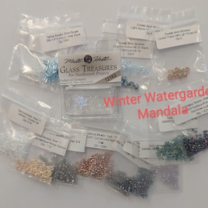 以下が含まれることがあります： 様々な色とサイズのデリカビーズのアソートメント。小さな透明な袋に梱包されています。ニードルワークプロジェクト用のMill Hill Glass Treasuresが含まれています。「Winter Watergarden Mandala」の文字が見えます。