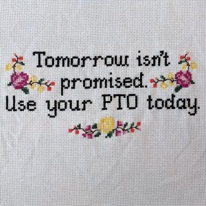 May include: Cross-stitch embroidery with the text "Tomorrow isn't promised. Use your PTO today." surrounded by yellow and pink flowers.